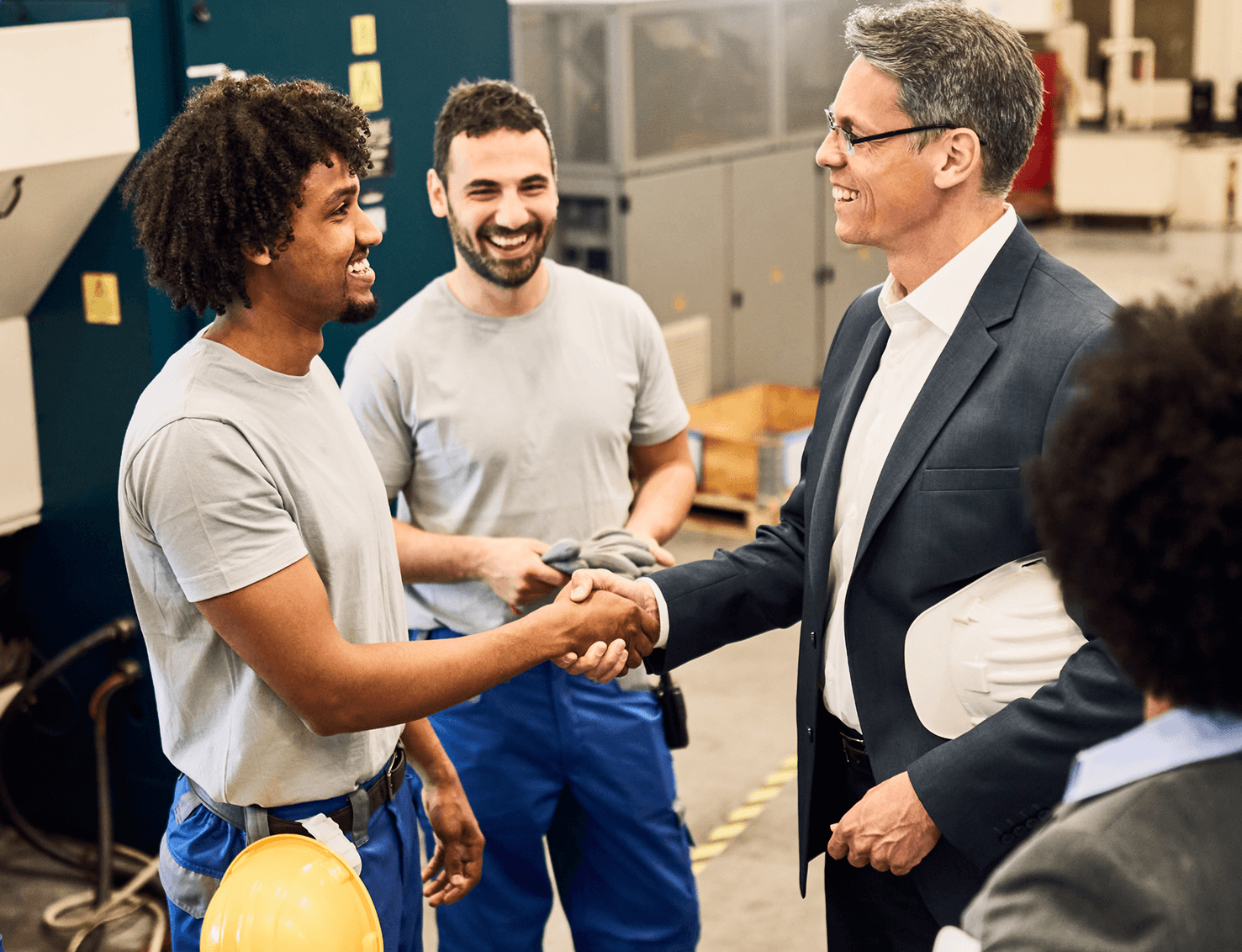 Happy corporate manager shaking hands with worker after staff meeting at factory.