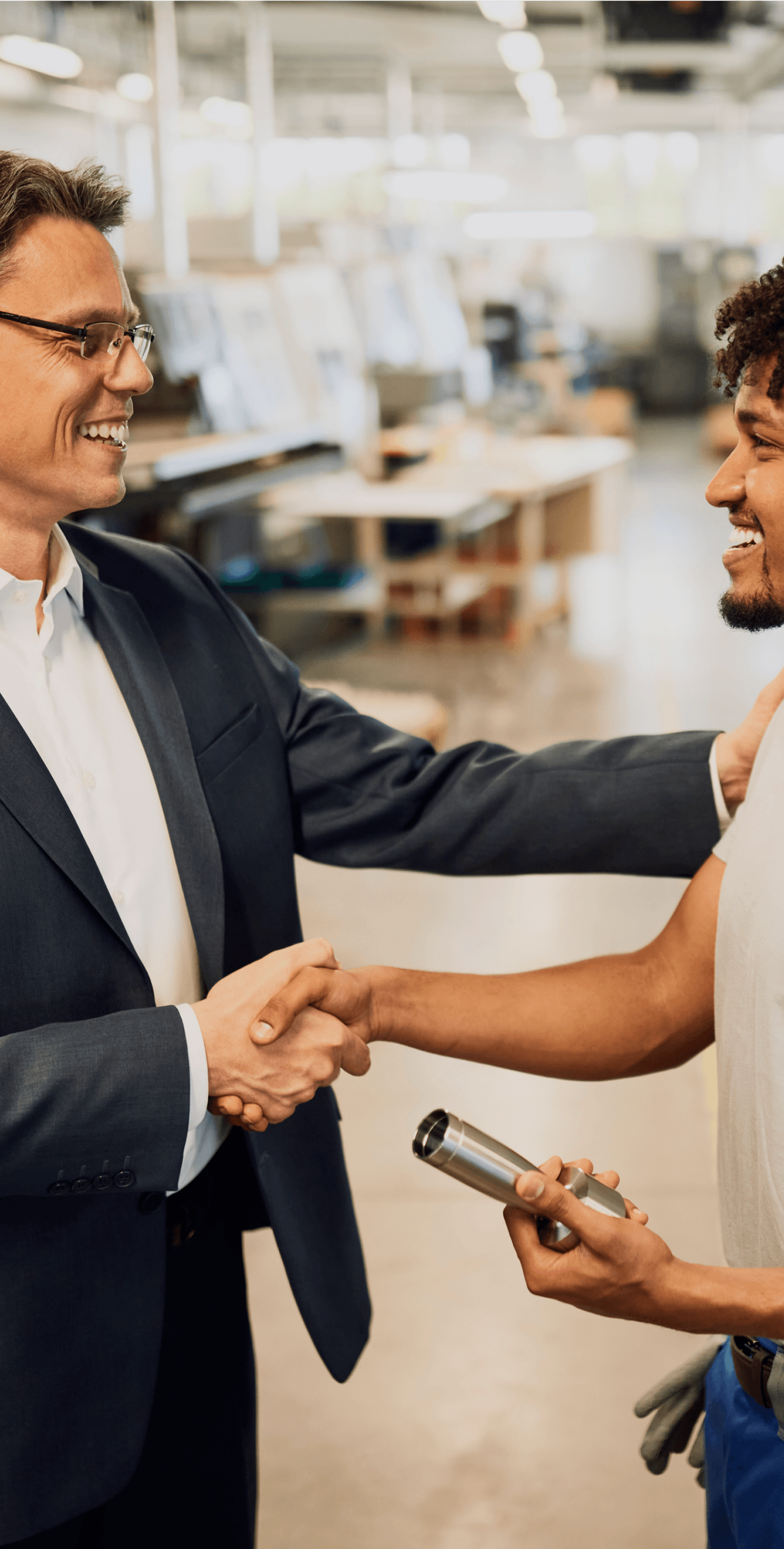 Happy corporate manager shaking hands with worker after staff meeting at factory.
